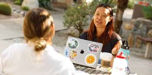 two students sit at a table deep in discussion in Scott courtyard